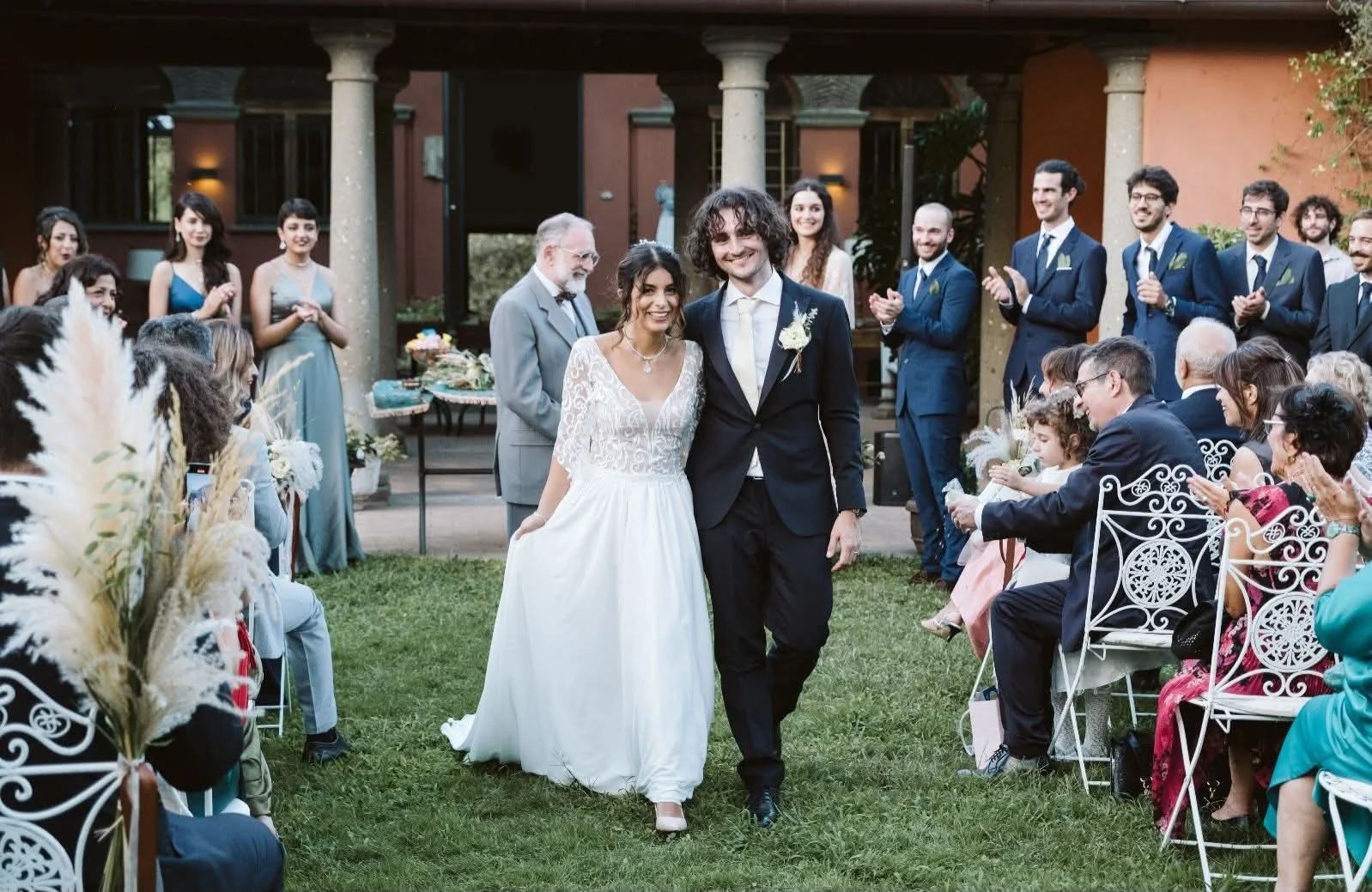Sposi sorridenti attraversano il giardino tra gli invitati