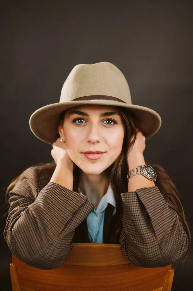 Donna con cappello beige e giacca sartoriale in un ritratto editoriale