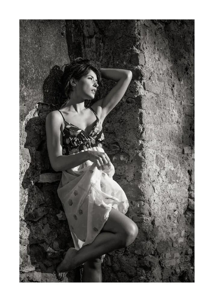 Fotografia di moda in bianco e nero, modella in posa accanto a una parete di pietra