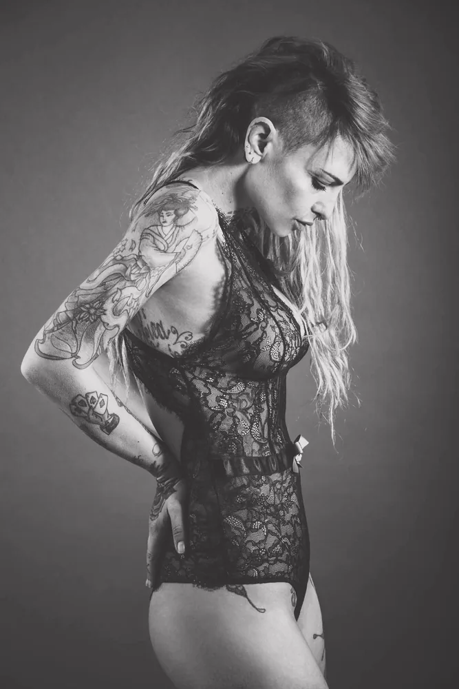 Fotografia di moda in bianco e nero di una modella tatuata in un completo di pizzo
