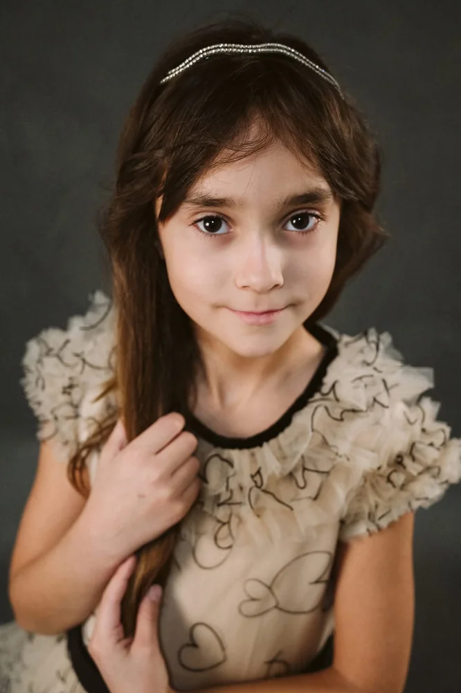 Ritratto in studio di una bambina con fermaglio nei capelli e abito chiaro