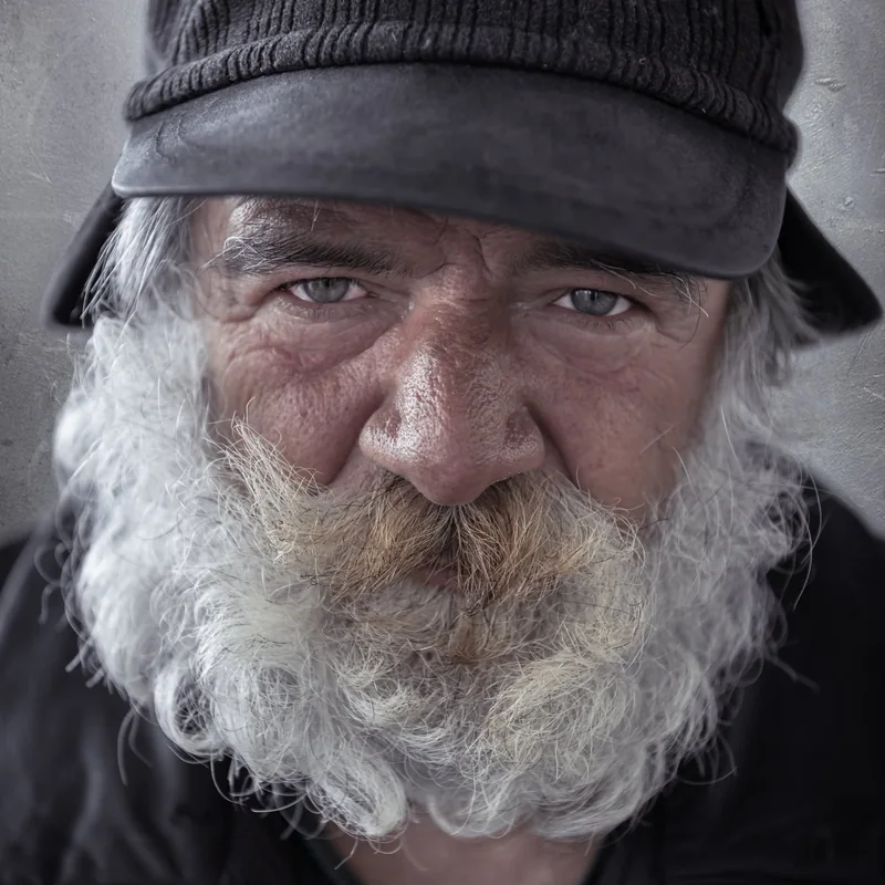 Primo piano di un uomo anziano con barba bianca e cappello scuro