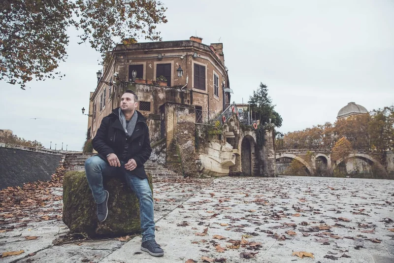 Ritratto ambientato di un uomo seduto sulla riva del Tevere a Roma