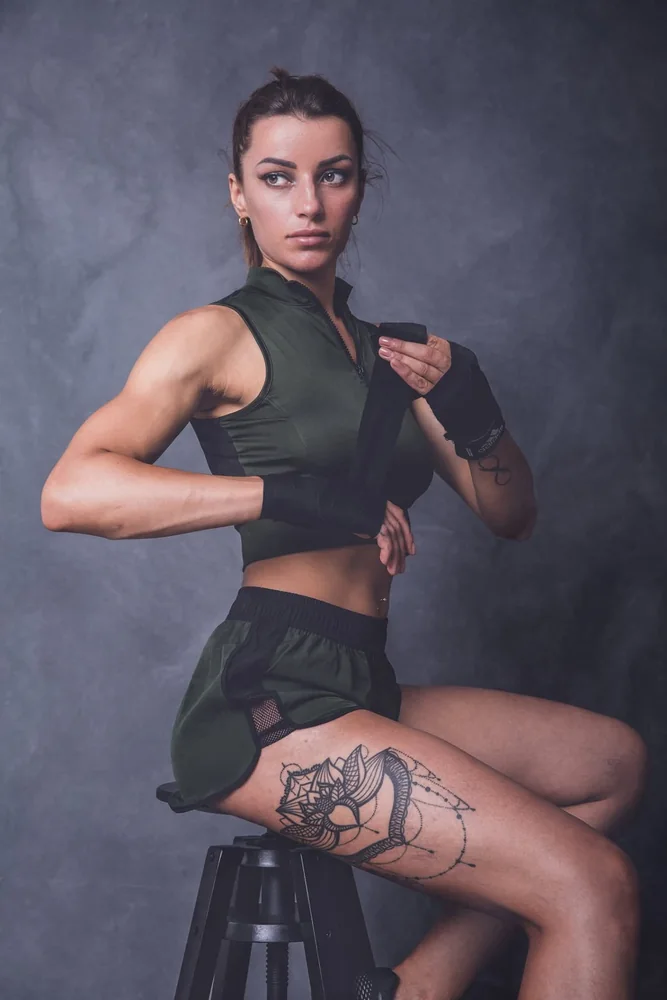 Ritratto in studio di una donna in abbigliamento sportivo, con fasce da allenamento alle mani