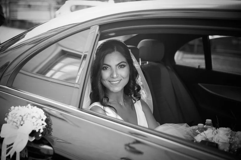 Sposa sorridente dal finestrino dell’auto, fotografia in bianco e nero