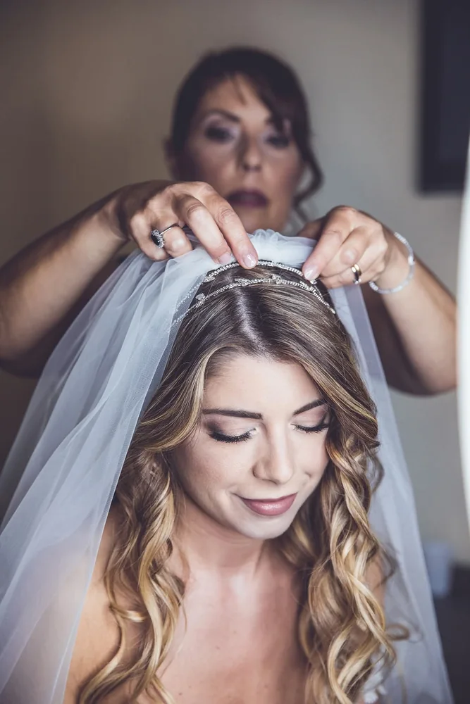 Una donna sistema il velo e il cerchietto della sposa durante i preparativi